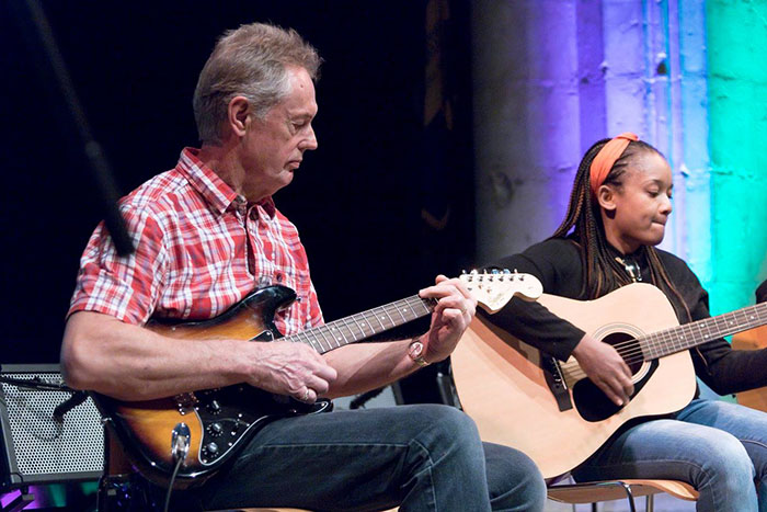 two adult guitar students on stage performing